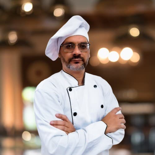 Chef Hugo Ferreira em uniforme de chef profissional, braços cruzados